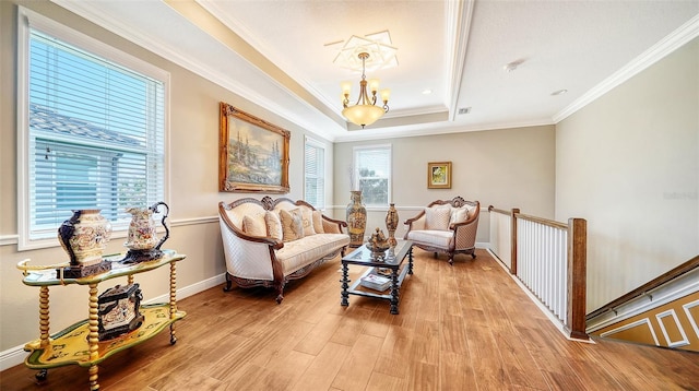 sitting room with a tray ceiling, ornamental molding, light hardwood / wood-style floors, and an inviting chandelier