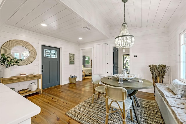 dining area featuring a chandelier, dark hardwood / wood-style flooring, and wooden walls