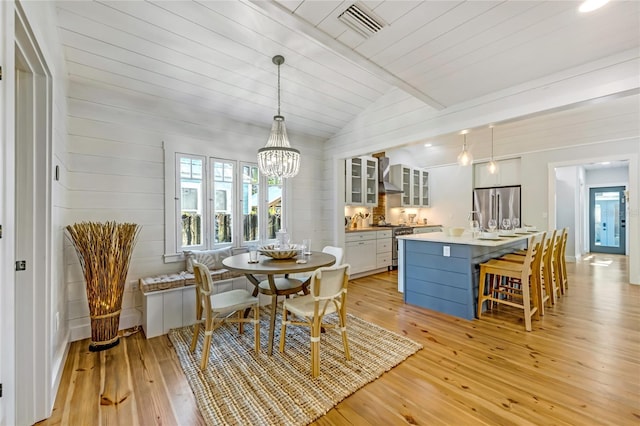 dining room featuring an inviting chandelier, light hardwood / wood-style floors, vaulted ceiling, and wood ceiling