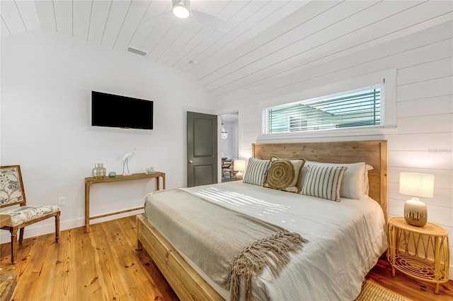 bedroom with wooden walls, light hardwood / wood-style flooring, wood ceiling, and lofted ceiling