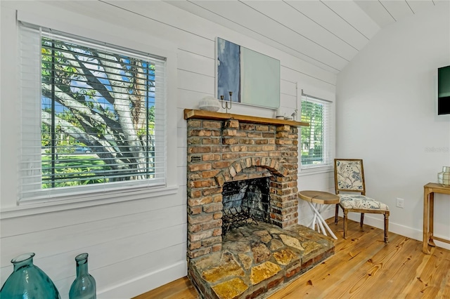 living room featuring wood-type flooring, a fireplace, a wealth of natural light, and vaulted ceiling