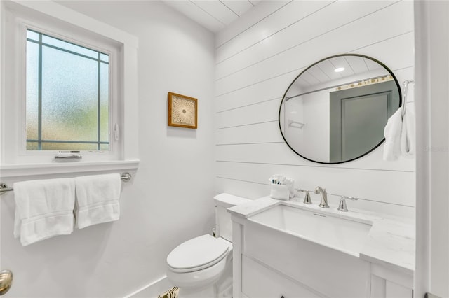 bathroom with wooden walls, vanity, and toilet