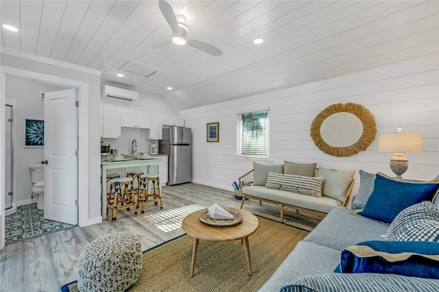 living room featuring wood walls, wooden ceiling, light hardwood / wood-style flooring, ceiling fan, and a wall unit AC