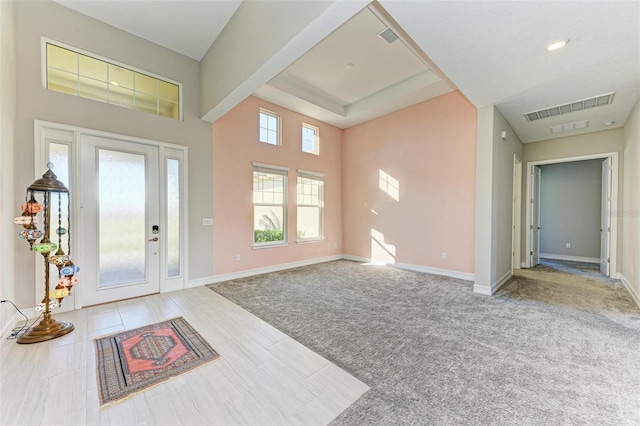 interior space featuring a towering ceiling and light colored carpet