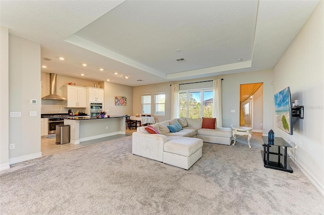 living room featuring light carpet and a tray ceiling