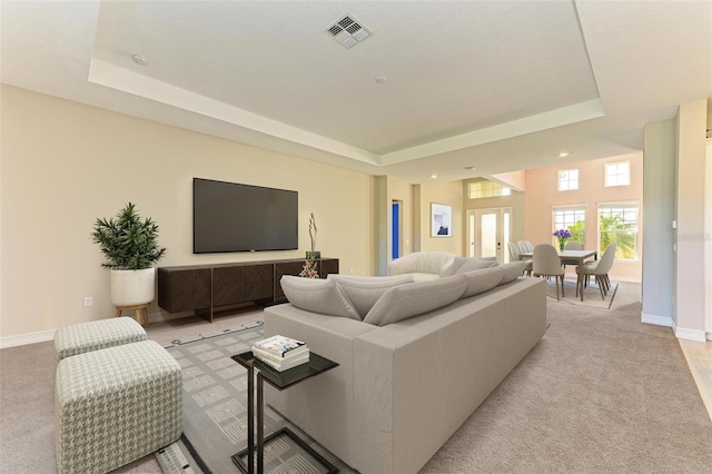 carpeted living room featuring french doors and a tray ceiling