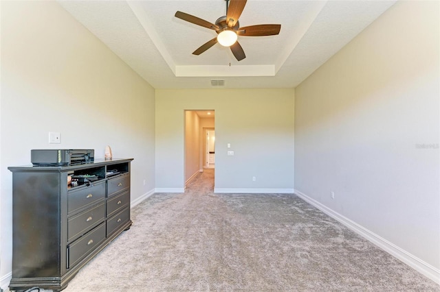 carpeted bedroom with a tray ceiling and ceiling fan