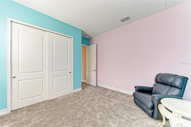 living area with light carpet and a textured ceiling