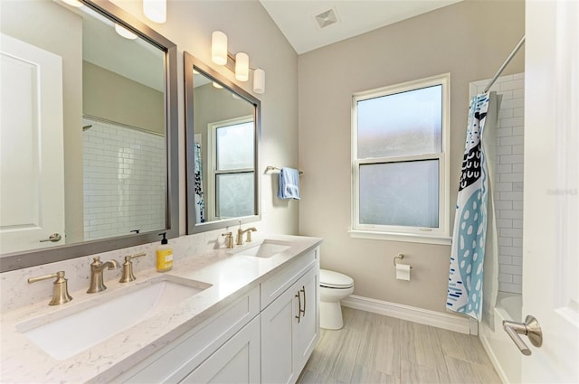 full bathroom featuring shower / bath combo with shower curtain, vanity, plenty of natural light, and toilet