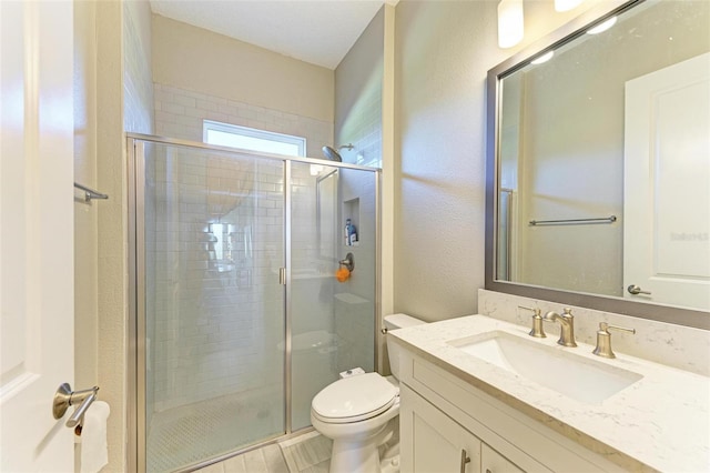 bathroom with a shower with door, vanity, and toilet