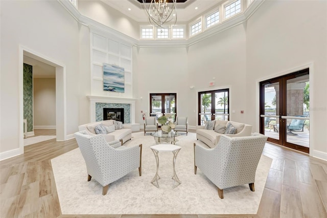 living room featuring a notable chandelier, light hardwood / wood-style floors, a high ceiling, and french doors