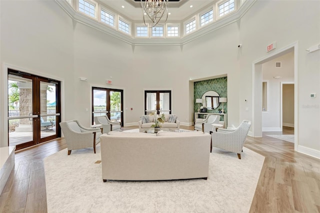 living room with french doors, hardwood / wood-style floors, a high ceiling, and an inviting chandelier