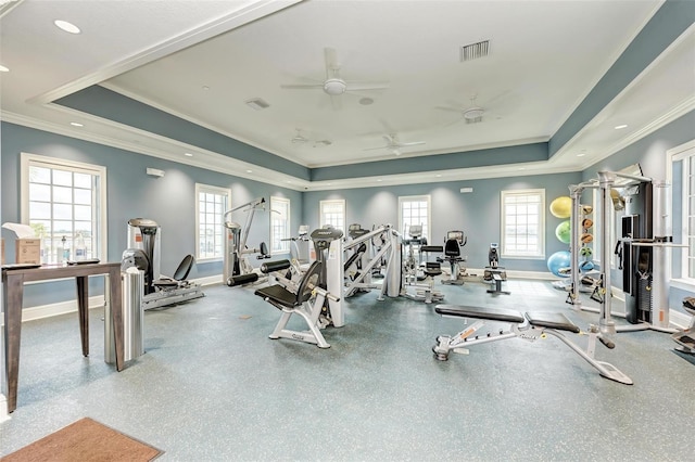 workout area with ceiling fan, a healthy amount of sunlight, and a raised ceiling