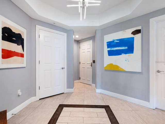 interior space featuring light tile patterned floors, a tray ceiling, and an inviting chandelier