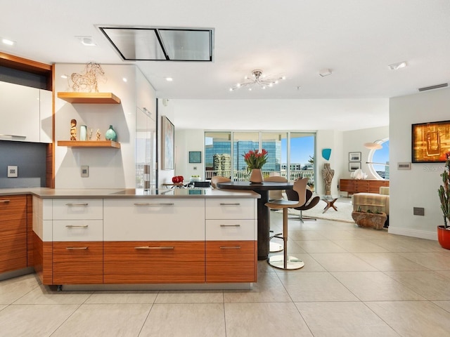 kitchen with white cabinets, a kitchen breakfast bar, a wall of windows, and light tile patterned floors