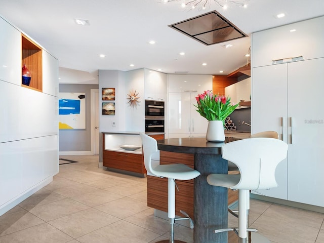 kitchen with double oven, white cabinets, and light tile patterned floors