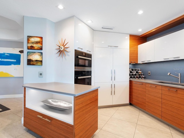 kitchen featuring white cabinets, light tile patterned floors, and sink