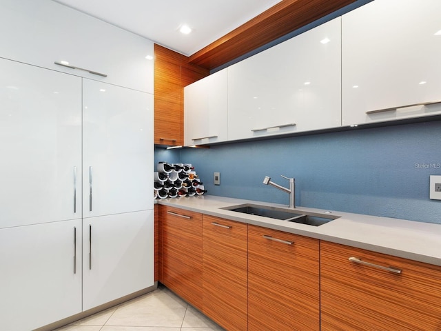 kitchen featuring white cabinets, light tile patterned floors, and sink