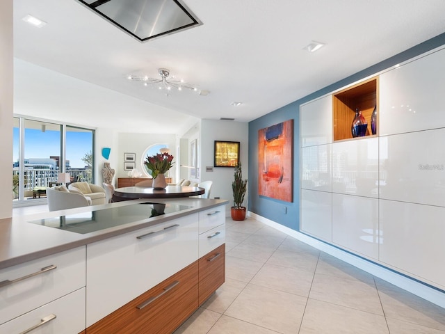 kitchen featuring white cabinets, cooktop, a wall of windows, and light tile patterned flooring