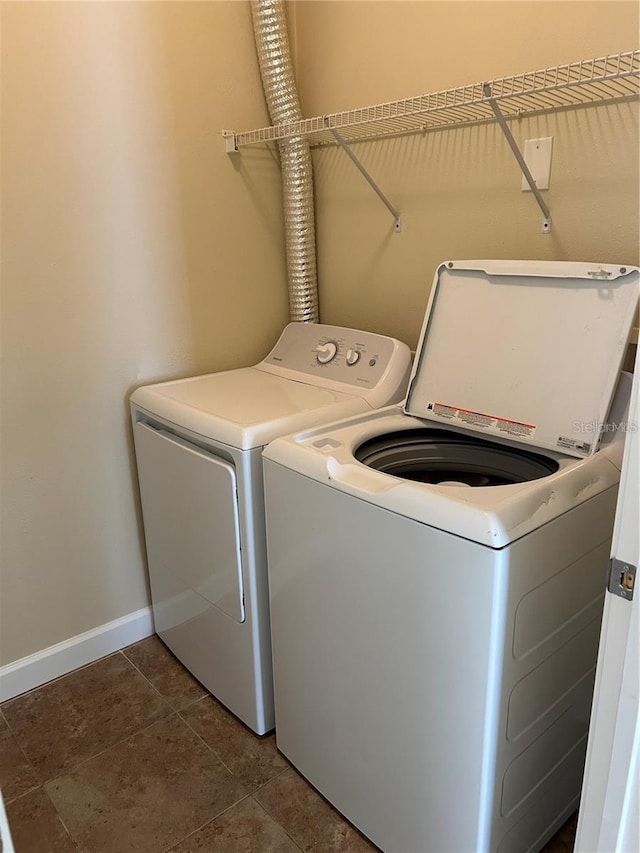 laundry area featuring washing machine and dryer and dark tile patterned floors