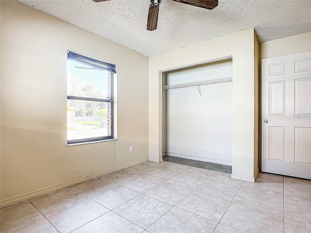 unfurnished bedroom featuring ceiling fan, a closet, light tile patterned floors, and a textured ceiling