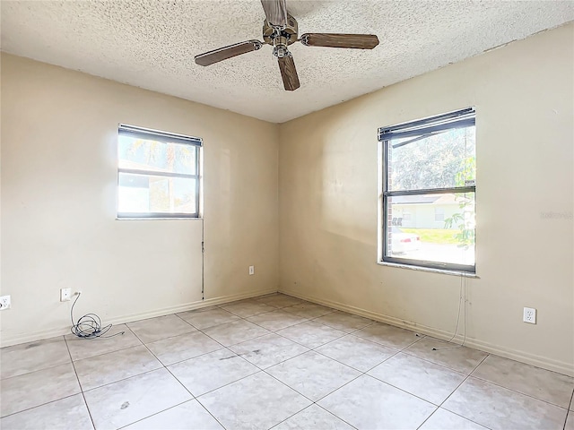 tiled spare room featuring ceiling fan, a textured ceiling, and a wealth of natural light