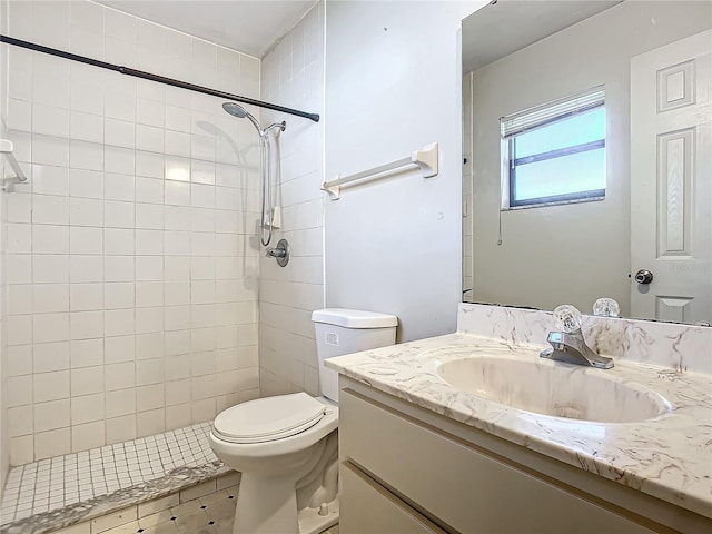 bathroom featuring a tile shower, vanity, and toilet