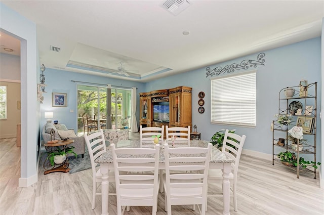 dining room with ceiling fan, light hardwood / wood-style floors, french doors, and a tray ceiling