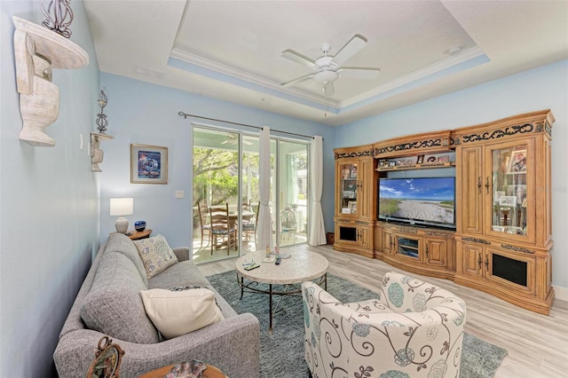 living room featuring a tray ceiling, ceiling fan, and light hardwood / wood-style floors