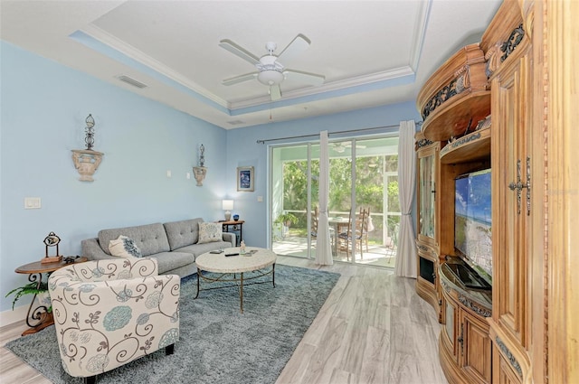 living room featuring ornamental molding, a tray ceiling, ceiling fan, and light hardwood / wood-style floors