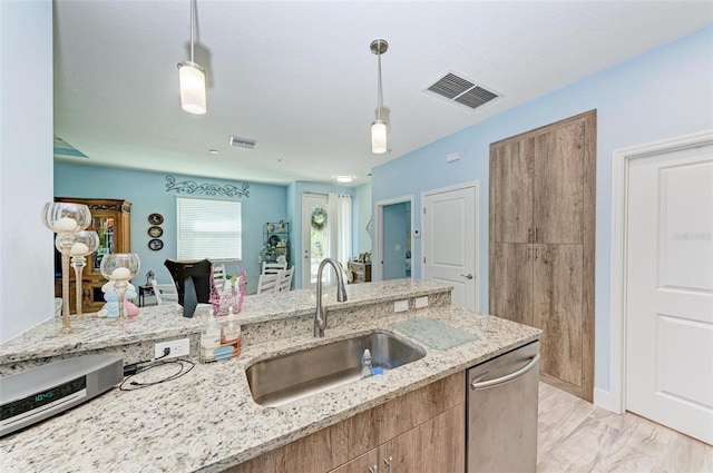 kitchen featuring sink, stainless steel dishwasher, light wood-type flooring, decorative light fixtures, and light stone counters