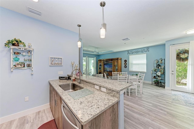 kitchen with pendant lighting, dishwasher, sink, a healthy amount of sunlight, and kitchen peninsula