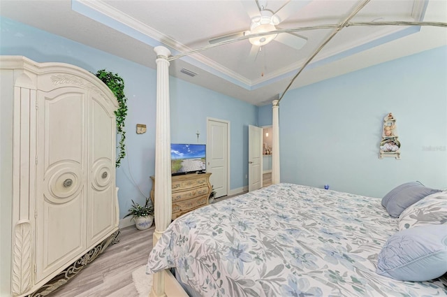 bedroom with ceiling fan, a raised ceiling, light wood-type flooring, and crown molding