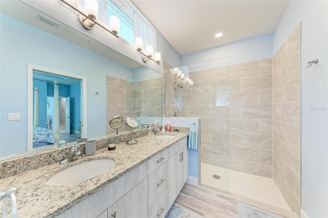 bathroom featuring a tile shower, vanity, and a textured ceiling