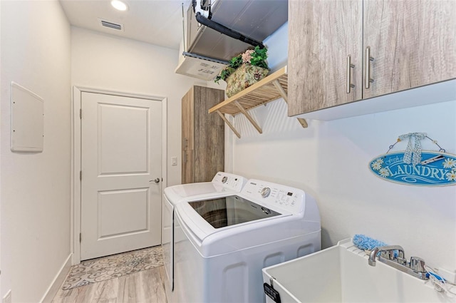 washroom with cabinets, light hardwood / wood-style floors, sink, washer and dryer, and electric panel