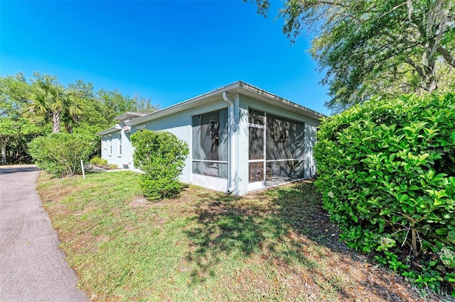 view of side of property featuring a lawn and a sunroom