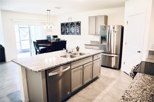 kitchen featuring gray cabinetry, sink, hanging light fixtures, stainless steel appliances, and an island with sink