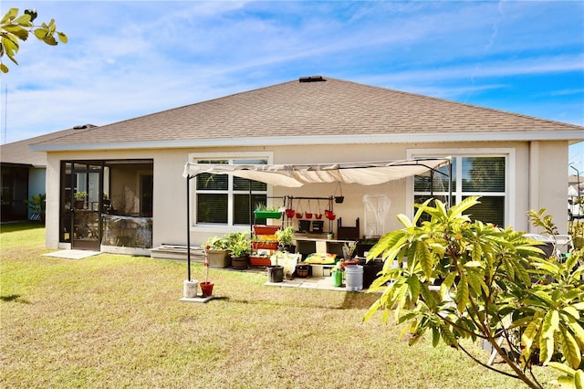 rear view of house featuring a yard and a sunroom