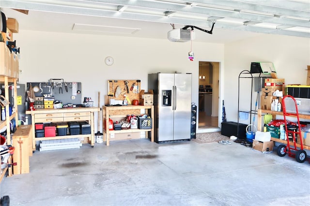 garage featuring stainless steel refrigerator with ice dispenser, a workshop area, and a garage door opener