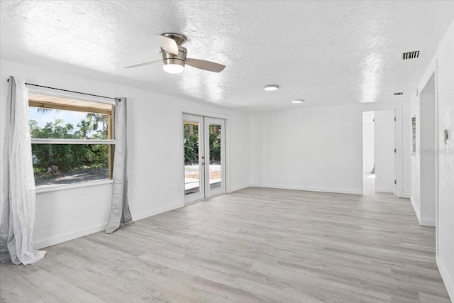 spare room featuring a textured ceiling, ceiling fan, light hardwood / wood-style flooring, and french doors