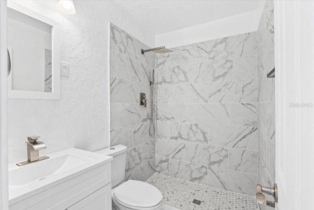 bathroom featuring vanity, toilet, and tiled shower