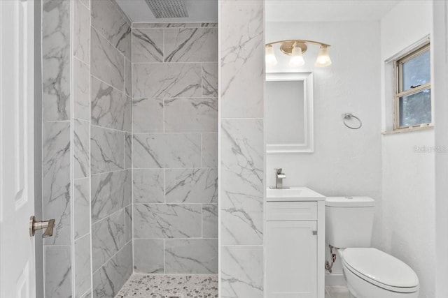 bathroom with toilet, vanity, and tiled shower