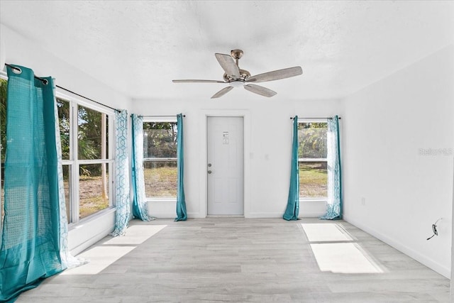 unfurnished room with ceiling fan, a textured ceiling, and light wood-type flooring