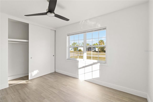 unfurnished bedroom with ceiling fan, light wood-type flooring, and a closet