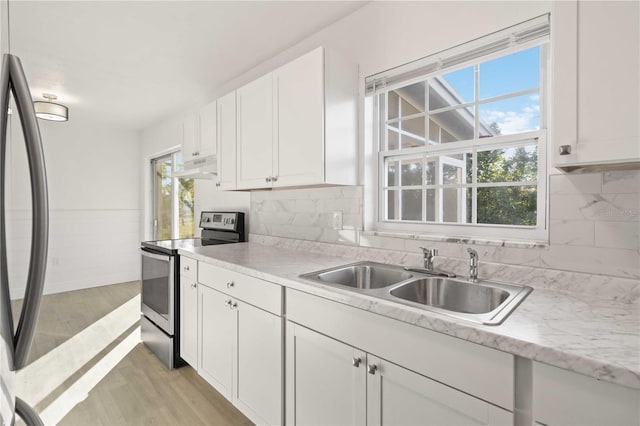 kitchen featuring sink, light hardwood / wood-style flooring, stainless steel appliances, tasteful backsplash, and white cabinets