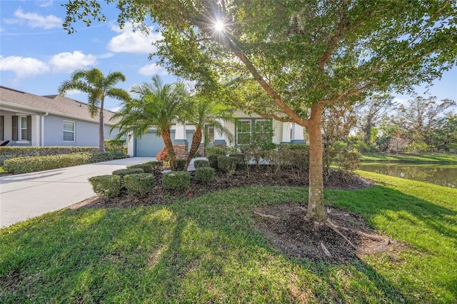 view of front of home featuring a garage, a water view, and a front lawn