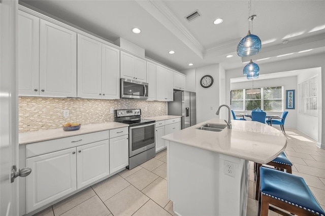 kitchen featuring appliances with stainless steel finishes, a tray ceiling, sink, decorative light fixtures, and white cabinets