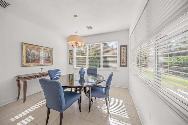 tiled dining space with a healthy amount of sunlight and an inviting chandelier