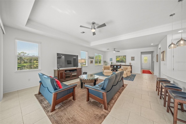 tiled living room featuring a tray ceiling, ceiling fan, and plenty of natural light