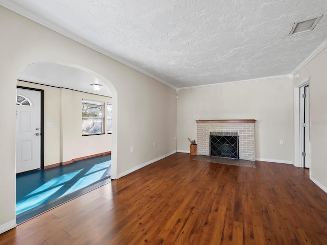 unfurnished living room with a textured ceiling, wood-type flooring, crown molding, and a brick fireplace